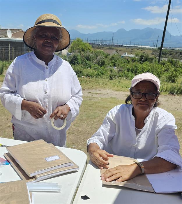 Katriena Griffies (links) en Catherine Jacobs het die warm dag getrotseer om Saterdag in Rosedale te help boeke oortrek.